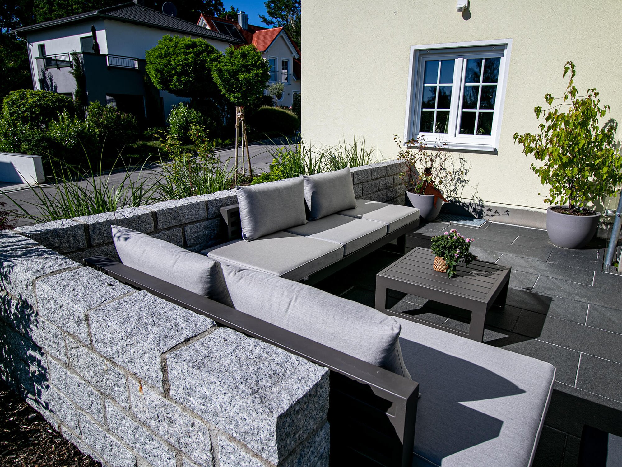 Outdoor-Sofa auf Terrasse eingegrenzt von Granitsteinmauer